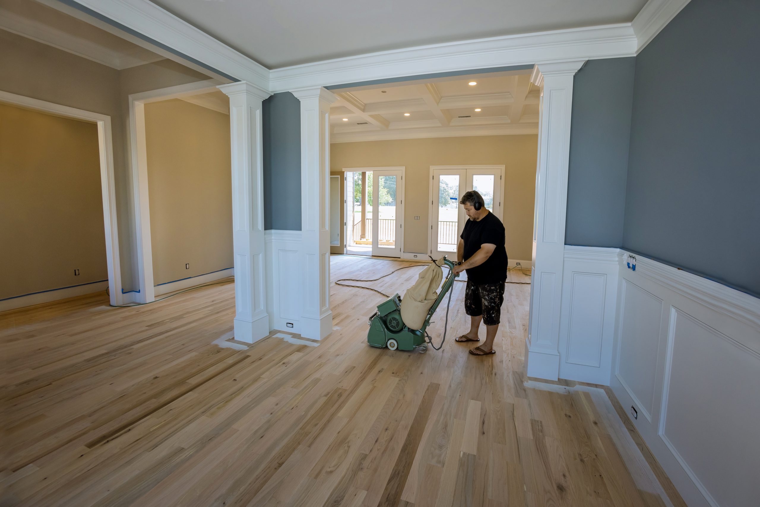 Flooring professional carrying out Wood Floor Sanding on a light oak hardwood floor inside a spacious South Woodford living area, using a drum sander.