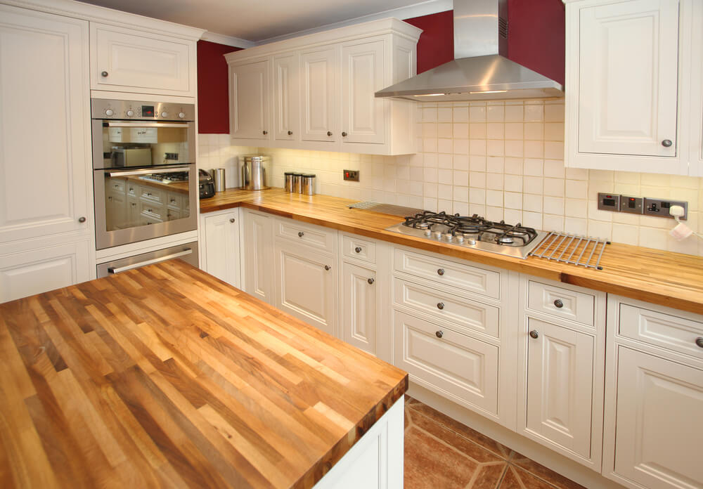 Freshly completed Worktop Refinishing in southwoodford, showing smooth oak butcher-block kitchen worktops above a warm ceramic tile kitchen floor in a classic cream cabinet kitchen.