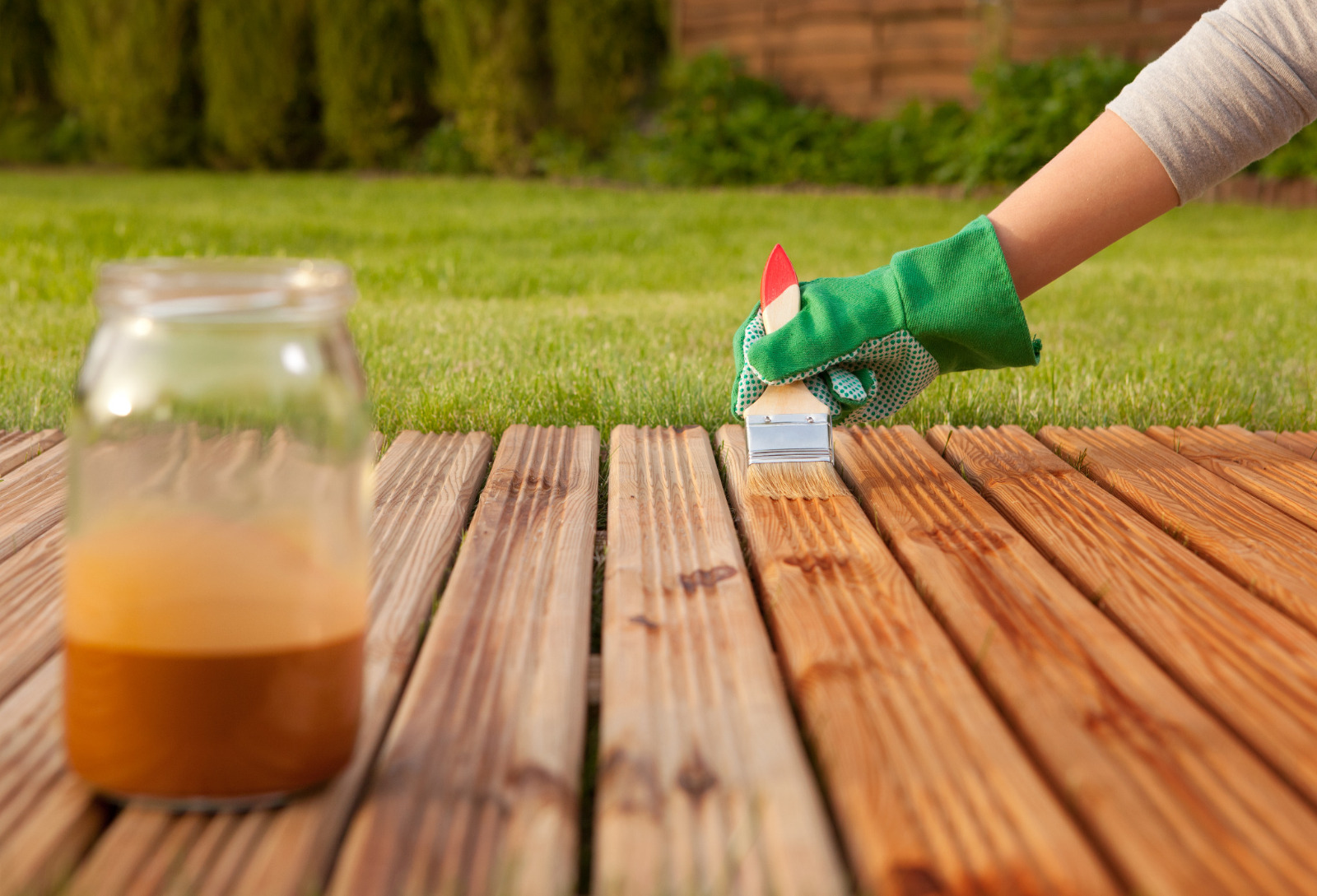 Applying protective oil after Deck Sanding in South Woodford on softwood timber garden decking, leaving the deck boards rich and refreshed.
