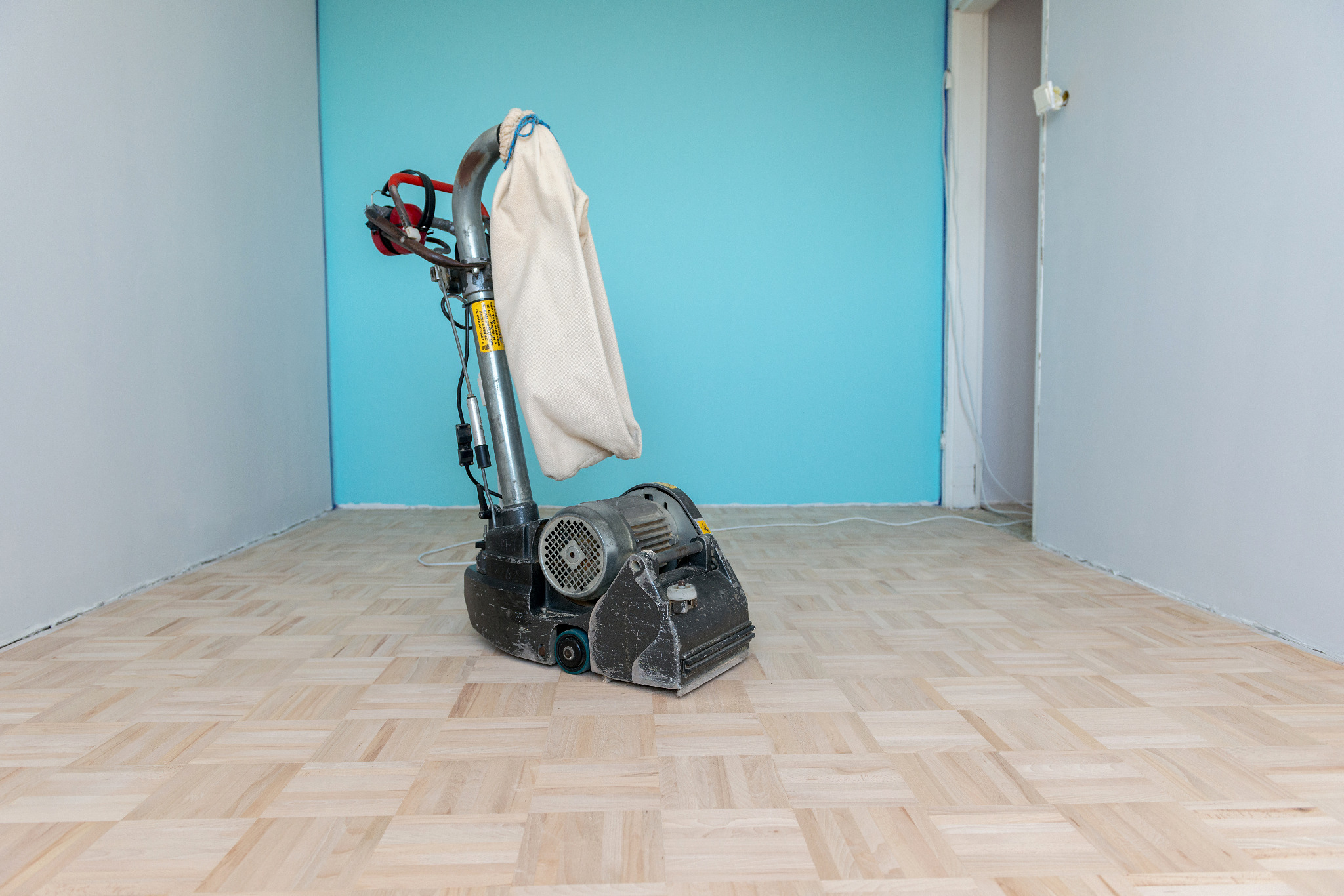 Wood Floor Sanding in Southwoodford with a professional floor sander working on a light oak mosaic parquet wood block floor during restoration.